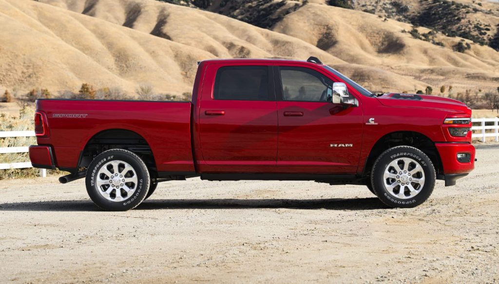 A red 2026 Ram 2500 truck parked on a road with a mountainous backdrop