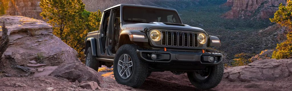 A 2026 Jeep Gladiator on rocky terrain with its doors removed.