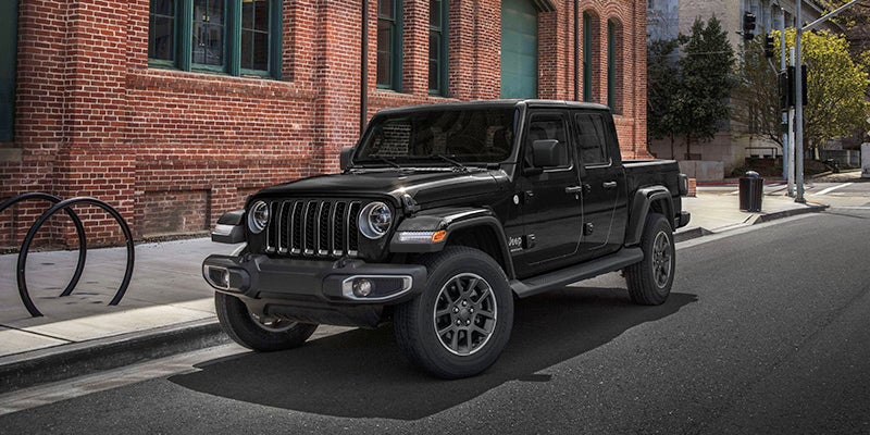 front left angle of a black 2024 jeep gladiator parked outside a building