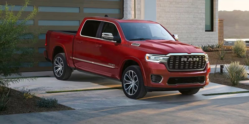 Red Ram pickup truck parked outside a modern home with desert landscaping.