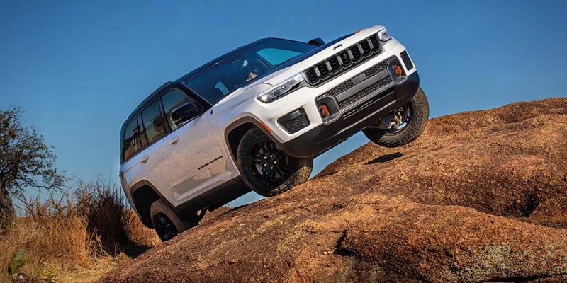 White Jeep SUV climbing over rocky terrain during an off-road adventure.